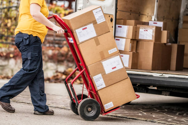 istock Female postal worker moving push cart 1159078602