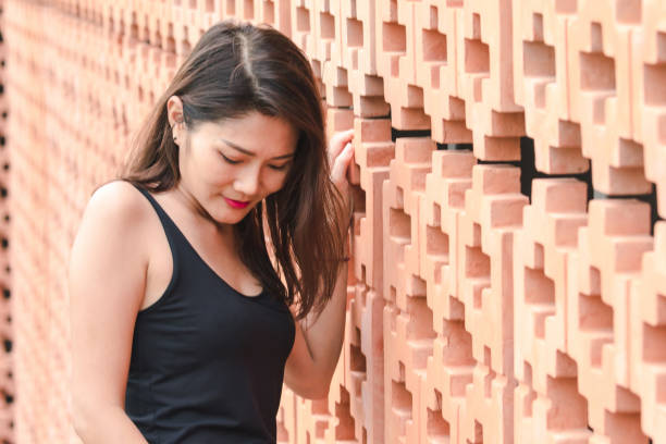 Portrait of a teenage girl standing in front of a brick wall holding her skateboard