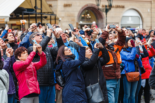 Prague, Czech Republic - 18 March, 2017: A multinational large crowd of tourists photograph on smartphones and look up at the city's landmark