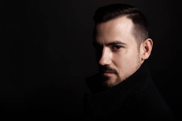 istock Handsome bearded man in a black coat. Black background. 1159082253