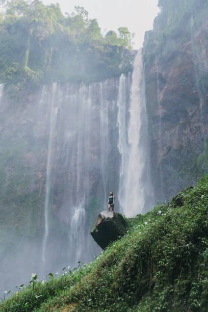 istock Woman standing and looking at Tumpak Sewu waterfall on Java 1159089388