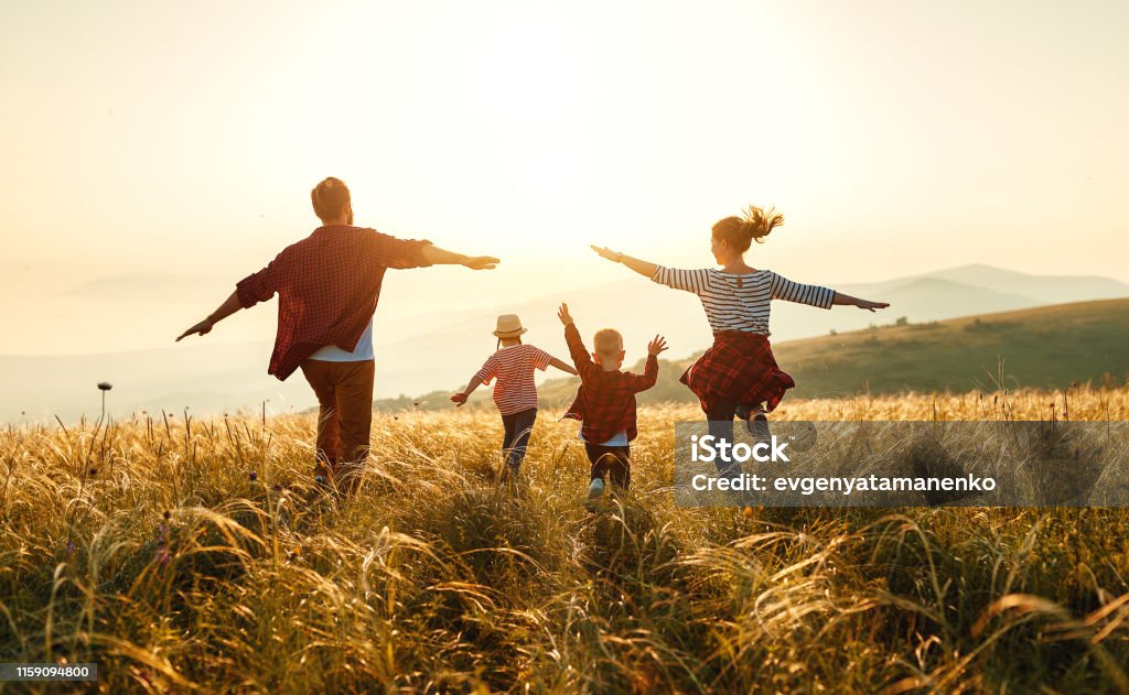 Familia feliz: madre, padre, hijo e hija de niños al atardecer - Foto de stock de Familia libre de derechos