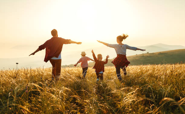 familia feliz: madre, padre, hijo e hija de niños al atardecer - niñez fotos fotografías e imágenes de stock