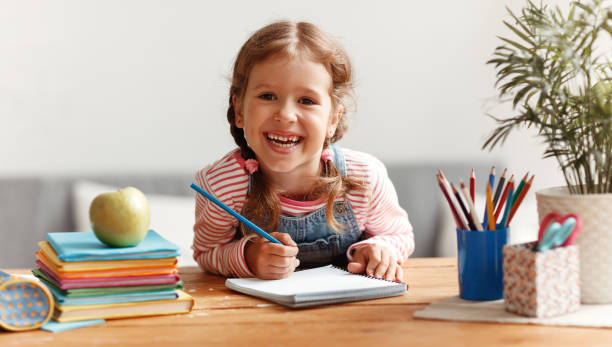 istock funny child  girl  doing homework writing and reading at home 1159094836