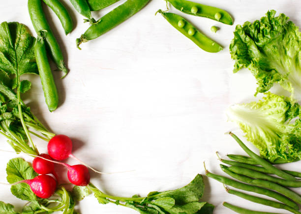 Spring vegetables on white wooden background with copy space. Radish, green peas, green beans and green salad - fresh harvest from the garden. Copy space.