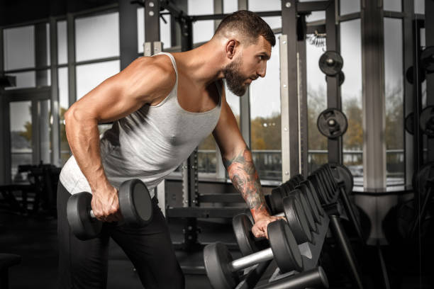 istock Bodybuilding. Bearded man exercising at gym with dumbbell concentrated side view 1159100874