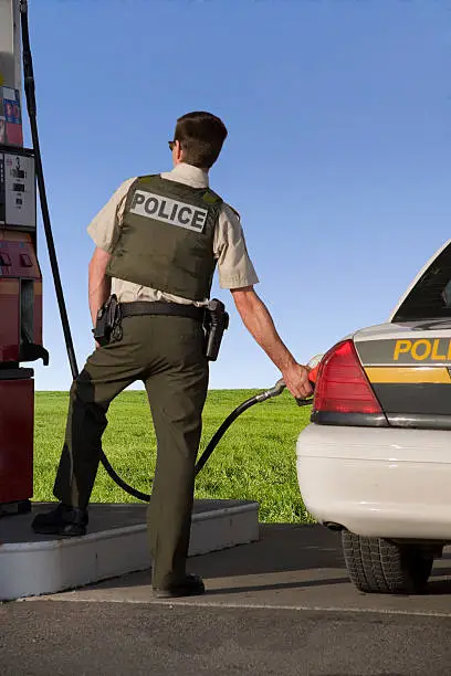 Policeman filling up his cruiser at the gas station.