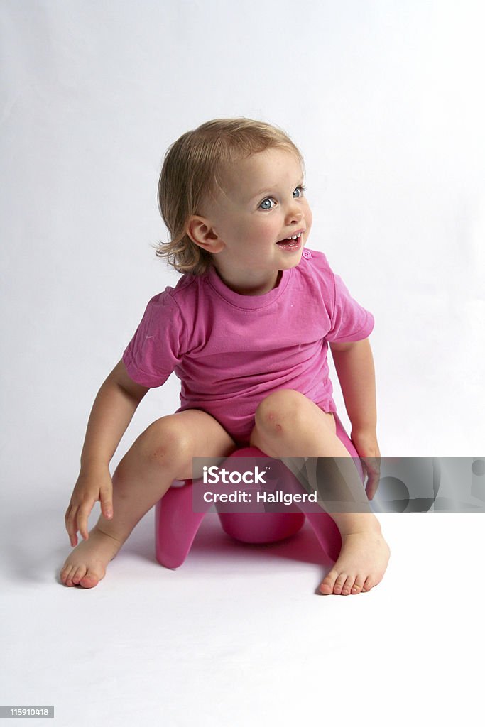 A picture of a little girl wearing pink on a pink potty Little baby and pink potty Baby - Human Age Stock Photo