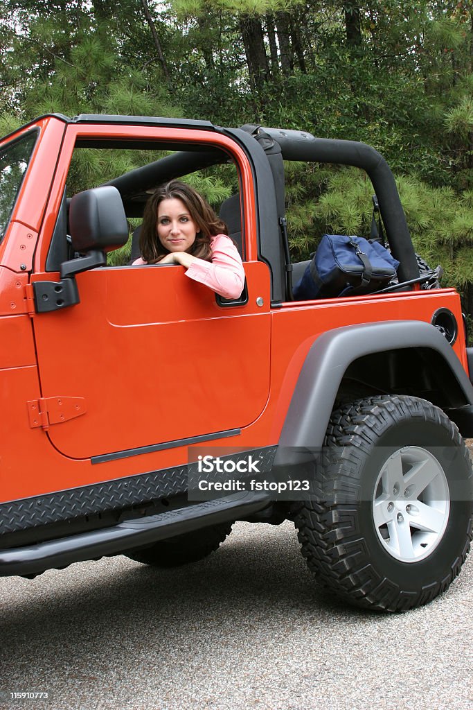 Woman driving red jeep outdoors. Summer road trip. Vehicle. Girl in orange jeep with bag in back ready for the road.  MORE LIKE THIS... in lightboxes below! 4x4 Stock Photo