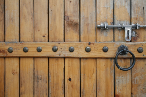 Metal original vintage wrought iron handle on an old wooden brown door with metal antique decor. Exterior decoration element.