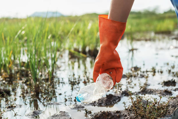 istock volunteer woman picking up garbage plastic for cleaning at river park 1159110893