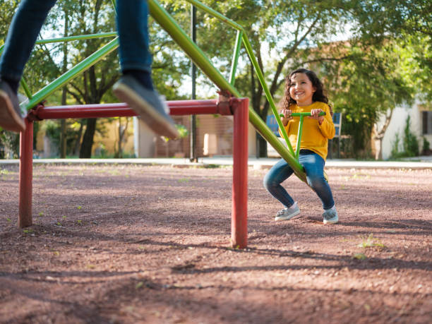 istock Little girl going up and down on a seesaw 1159111716