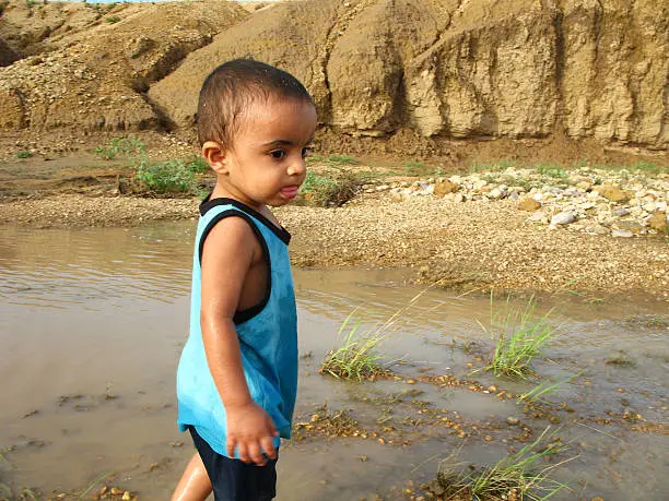 Photo of Asian kid playing in stream of water