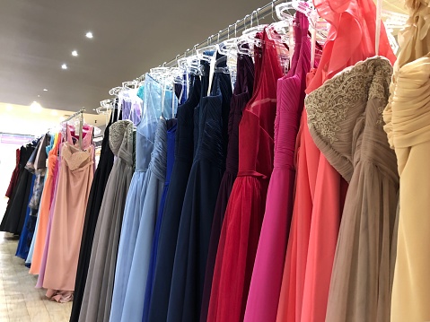 Unrecognisable dresses in many bright hues, all in a row