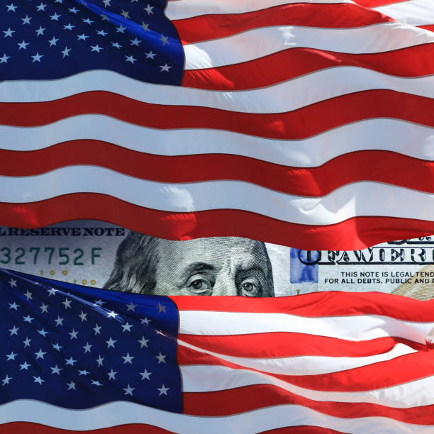 istock waving American flags and one hundred US dollar bill 1159117118