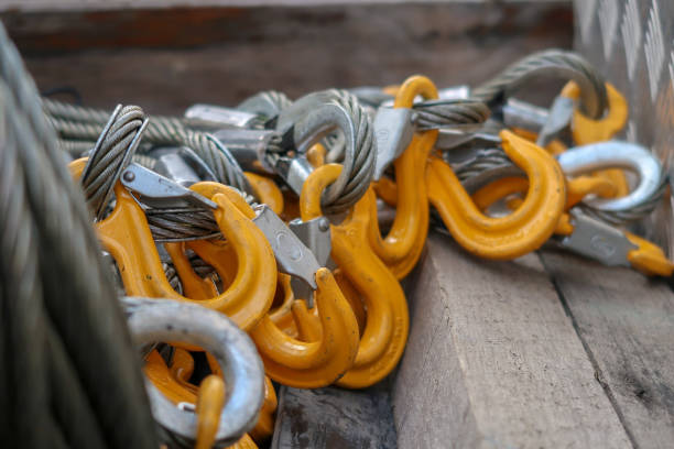 Rigging Equipment Hooks and Wire Slings Closeup of Lifting Equipment - Yellow Grade 80 Sling Hooks attached to Wire Rope Slings. Shallow depth of field hook equipment stock pictures, royalty-free photos & images