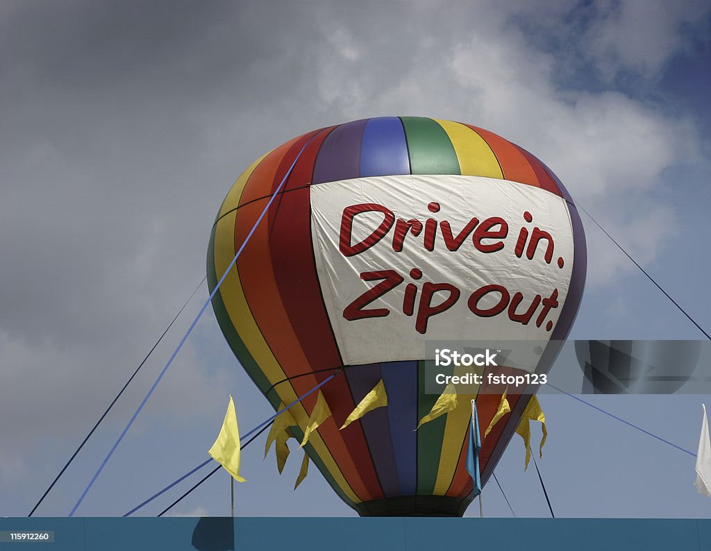 Grand Opening balloon on building top. Drive-in, zip out. Colorful. Colorful Giant balloon on building top with sign that reads NOW OPEN.   MORE LIKE THIS... in lightboxes below. Advertisement Stock Photo