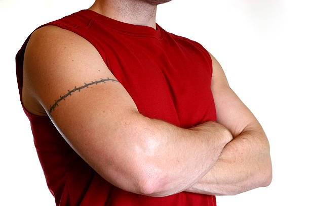 uomo in maglietta rossa con braccia incrociate e tatuaggio - arm tattoo foto e immagini stock