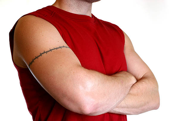 Man in red shirt with arms crossed and tattoo Muscled Man with arms crossed, tattoo on arm. chest tattoo men stock pictures, royalty-free photos & images
