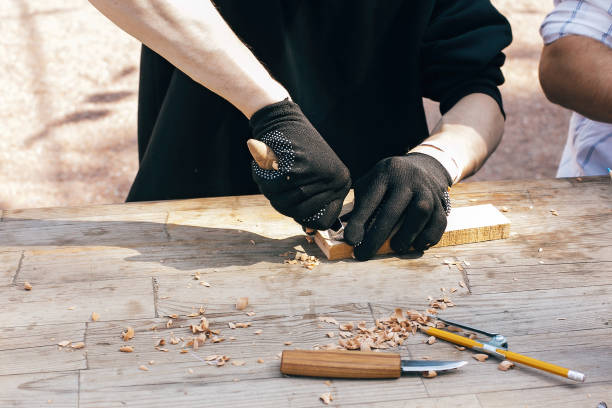 istock Wooden workshop. Hands carving spoon from wood, working with chisel close up. Process of making wooden spoon, chisel, pencil, compass, ruler on dirty table with shavings 1159128134