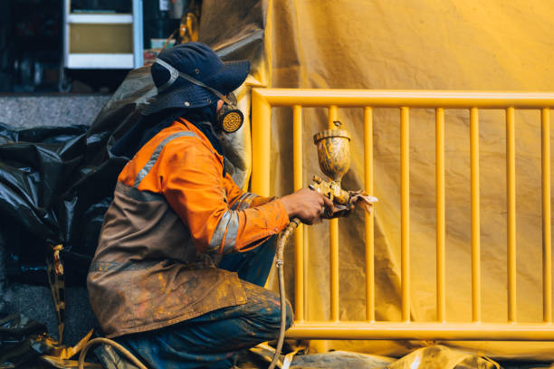 worker painting a wall yellow - house painter paint roller yellow painting imagens e fotografias de stock