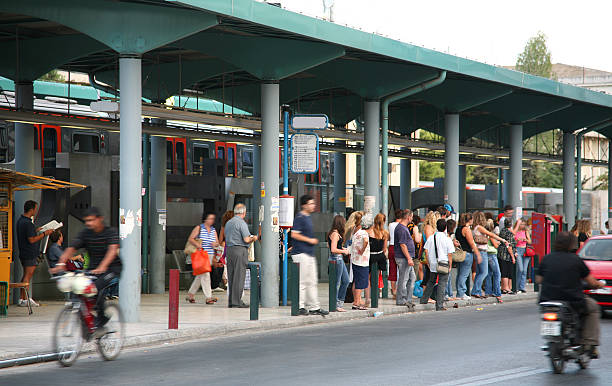 istock People waiting at a busy bus stop, with train in background 115913656