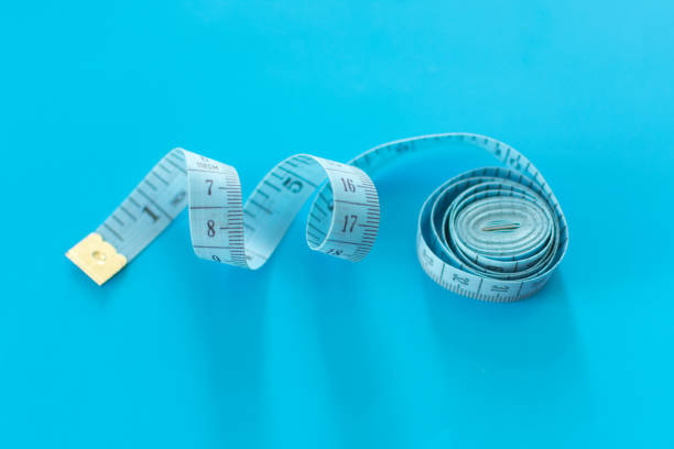 istock Roled blue measuring tape on blue background. 1159138136
