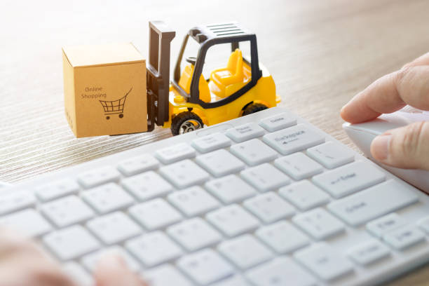 istock Mini forklift truck load cardboard box with text online shopping and hand using mouse and white keyboard nearby. Logistics and transportation management ideas and Industry business commercial concept. 1159138312
