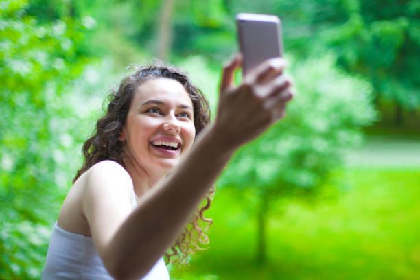 istock Young smiling girl is making selfie on a camera 1159140302