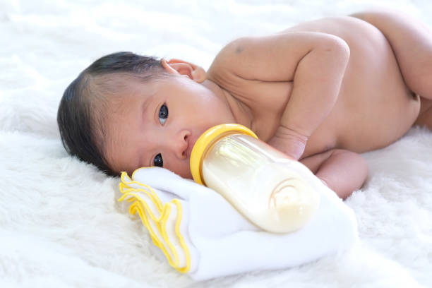 istock Babies on a white prom bed are sucking milk in a bottle. 1159141333