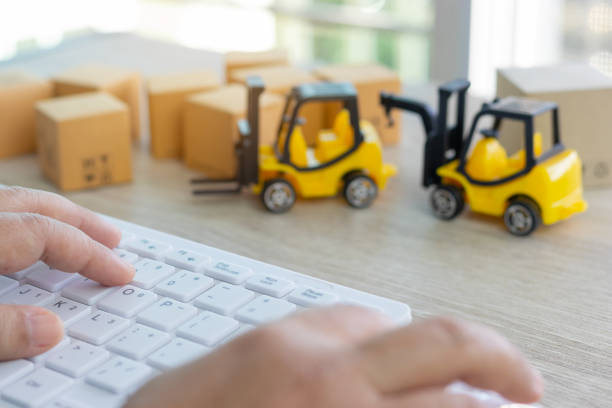 istock Hand using mouse and keyboard and stack of boxes and mini forklift truck nearby. Consumer can buy product directly anywhere anytime from seller using web browser. Online shopping and ecommerce concept 1159144955