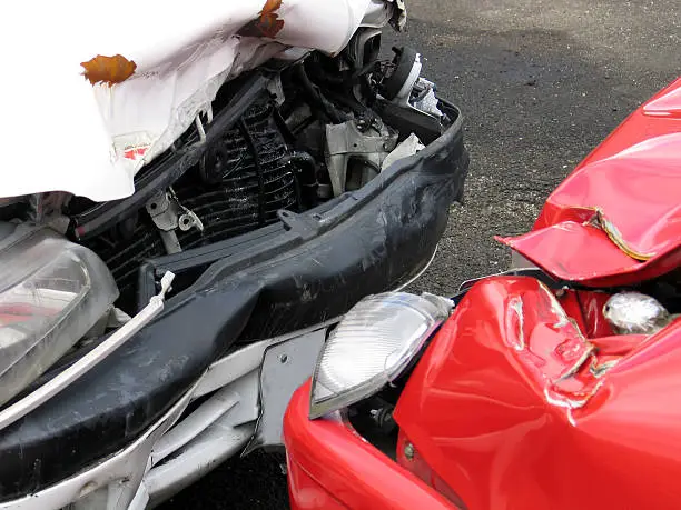 Photo of Front of a red car and the front of white car smashed up