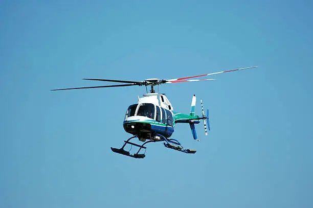 Four rotor, seven passenger helicopter against a clear sky. This helicopter is also used as an air ambulance. Bell 407.