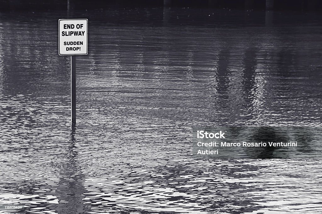 End of slipway - sudden drop! - Flooded area This sign is in the middle of the water! Blue duotone. Bizarre Stock Photo