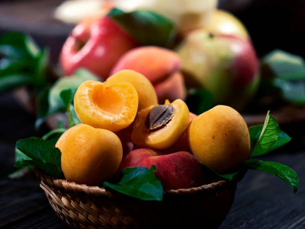 Fresh red apples, peaches and apricots on the wooden table