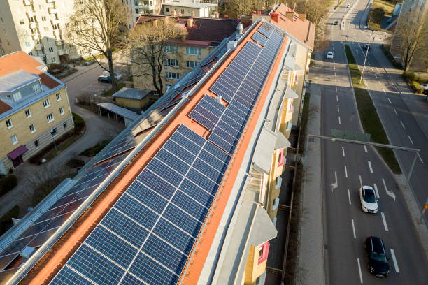 vue supérieure du système de panneaux voltaïques de photo solaire bleue sur le dessus élevé de toit d'immeuble d'appartement le jour ensoleillé. concept de production écologique renouvelable d'énergie verte. - voltaic photos et images de collection