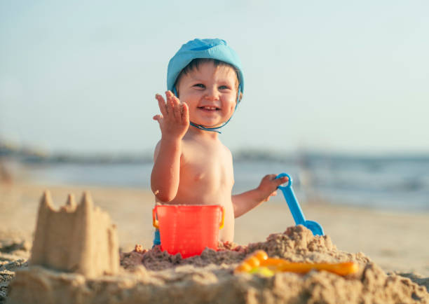 glücklicher kleiner junge beim bau einer sandburg am strand - lifestyles child beach digging stock-fotos und bilder