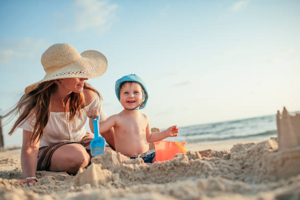 mutter und sohn am strand spielen mit sand - sandburg struktur stock-fotos und bilder