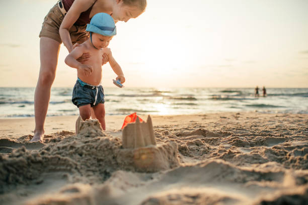 istock Sister with little brother on the beach playing with sand 1159161950