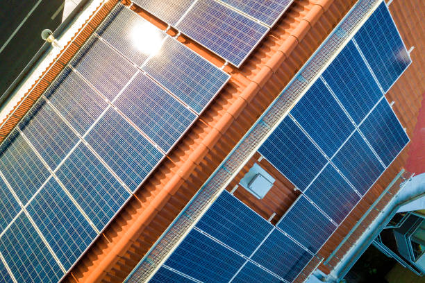 aerial view of solar photo voltaic panels system on apartment building roof. renewable ecological green energy production concept. - solar panels house imagens e fotografias de stock