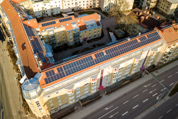 top view of blue solar photo voltaic panels system on high apartment building roof top on sunny day. renewable ecological green energy production concept. - voltaic imagens e fotografias de stock