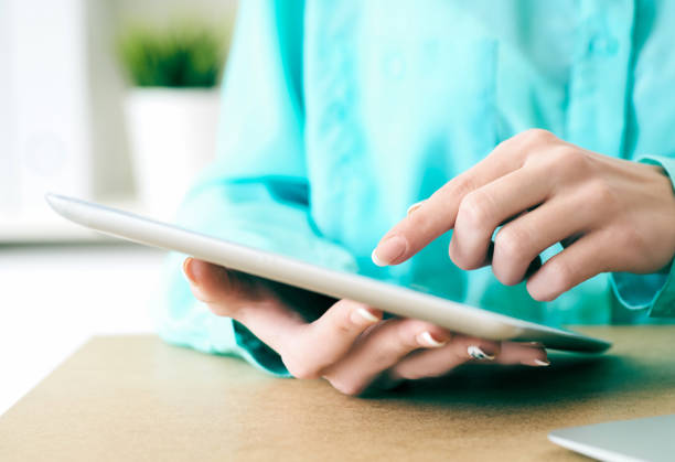 istock Close-up of female hands working with tablet computer. Woman using social network, texting and blogging. 1159168268