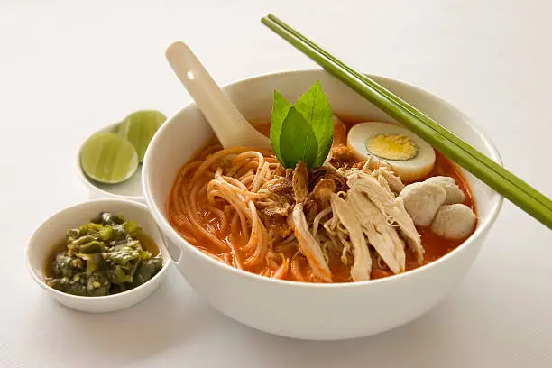 Famous spicy Singapore Laksa complete with sliced lemon and hot green chili.