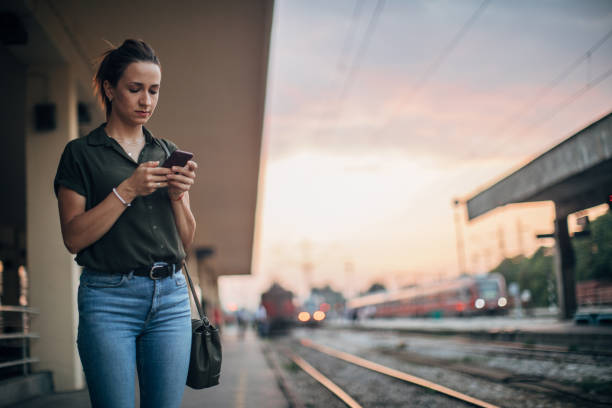 mujer esperando tren y enviando mensaje - ponytail brown hair tourist women fotografías e imágenes de stock