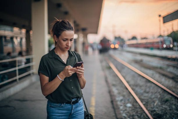 donna in attesa del treno e con lo smartphone - ponytail brown hair tourist women foto e immagini stock