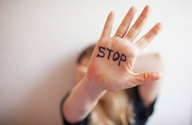 女性は手のひらに刻印で手のひらを示す 「停止」 - 虐待 ストックフォトと画像
