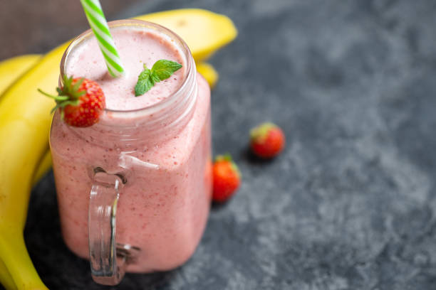 smoothie aux fraises ou milkshake sur la table avec copyspace. petit déjeuner rouge d'été - cocktail à la fraise photos et images de collection