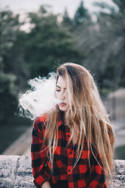 istock Young blond woman portrait vaping 1159172357