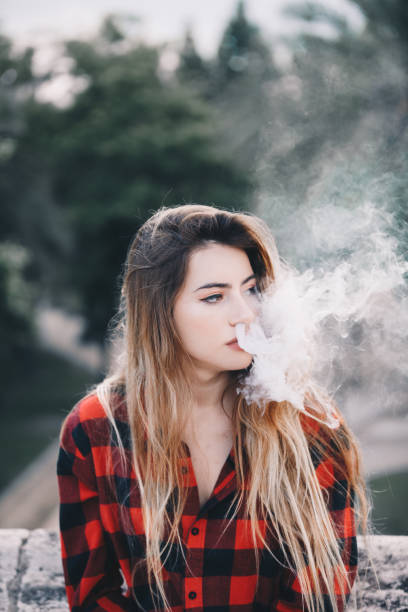istock Young blond woman portrait vaping 1159172888