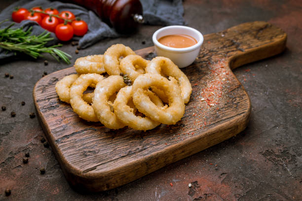 Rings of squid in batter with sauce Rings of squid in batter with sauce on the board on dark concrete rustic background calamari photos stock pictures, royalty-free photos & images